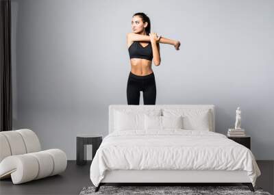 Full length portrait of beautiful young woman doing stretching exercise isolated over gray background Wall mural